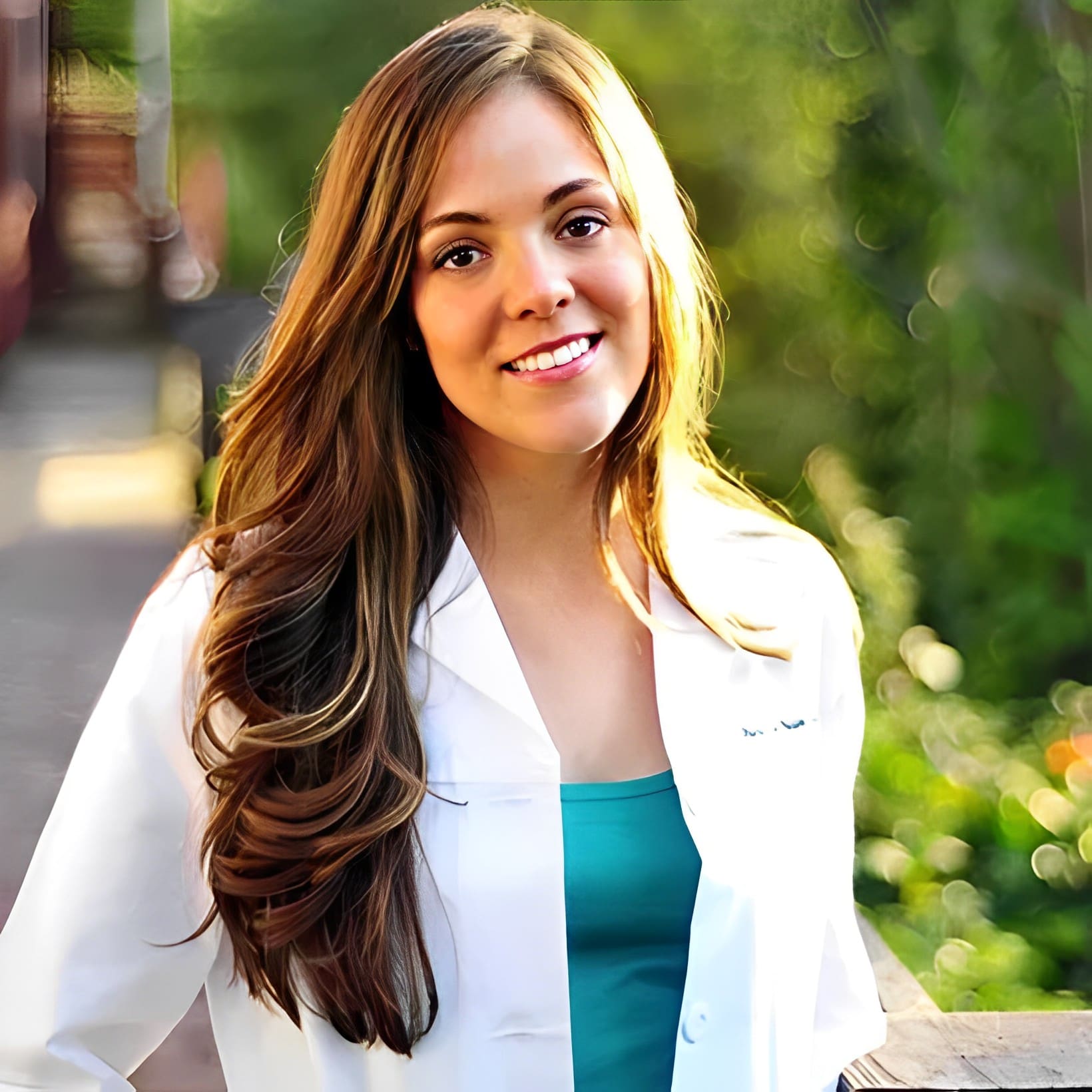 Smiling woman in white coat outdoors.